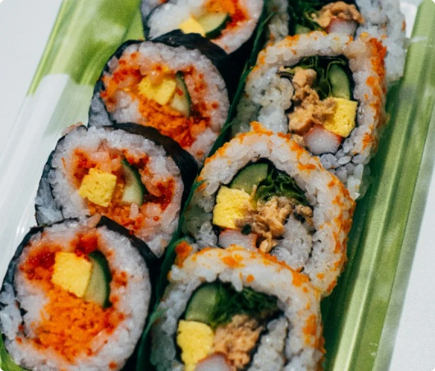 Overhead view of two sushi rolls, one with seaweed on the outside, and one with rice on the outside.